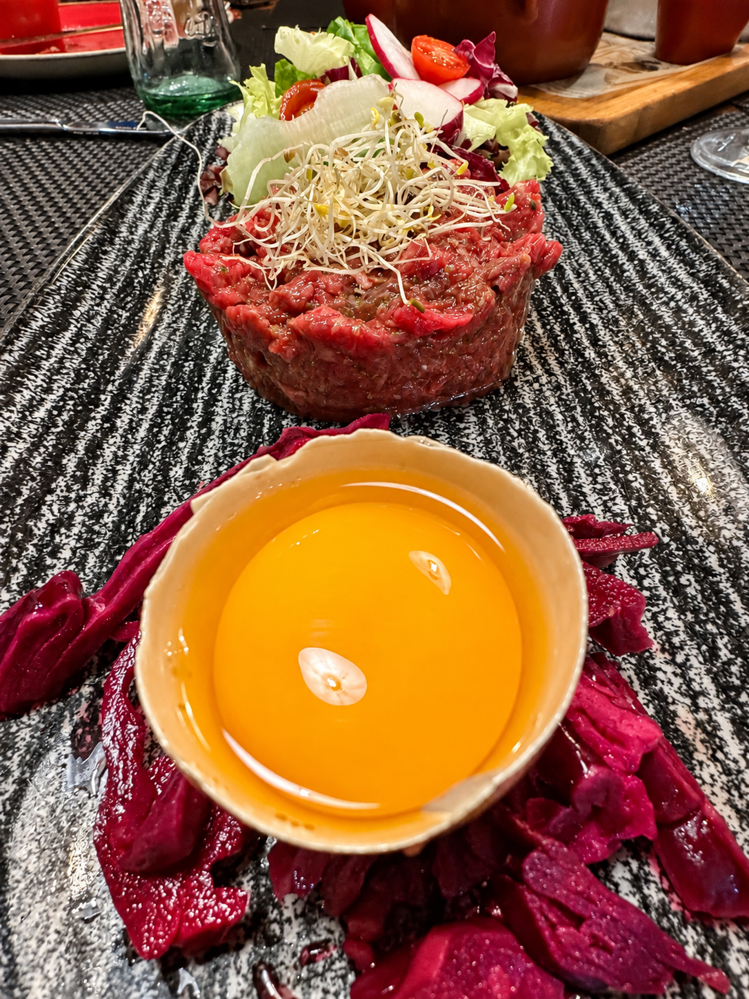 Steak tartar con yema de huevo y ensalada en un plato estampado