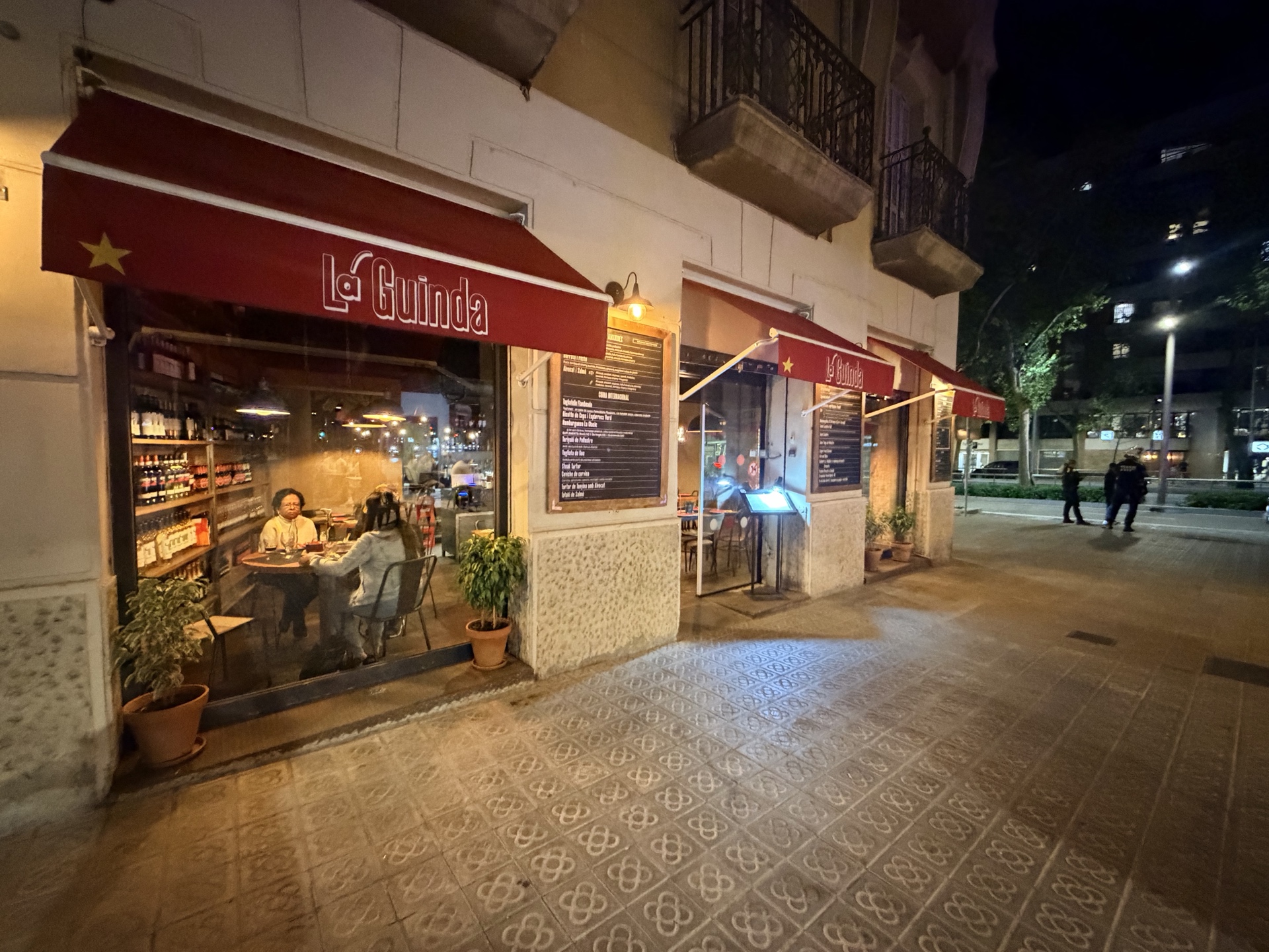Los toldos rojos y la fachada iluminada de La Guinda en una noche de Barcelona